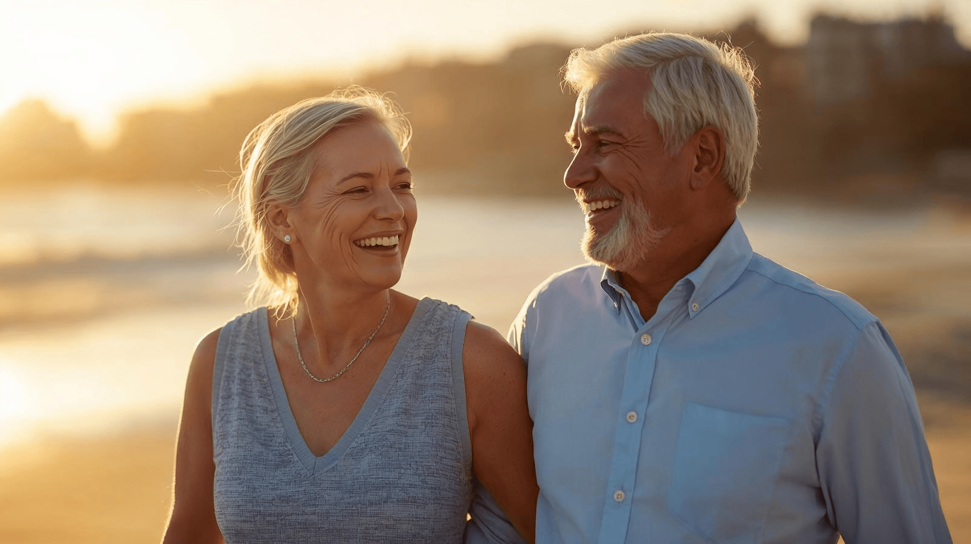 Retired couple walking on a beach at sunset